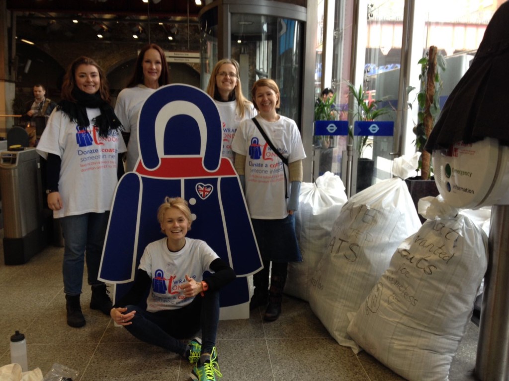 1st blog post image - A group of people with a cardboard cut out of a coat surrounded by sacks of coats