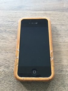 An iPhone 4 in a bamboo case on a wooden surface