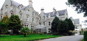 A large victorian building, 3 stories high in grey stone with a slate roof.