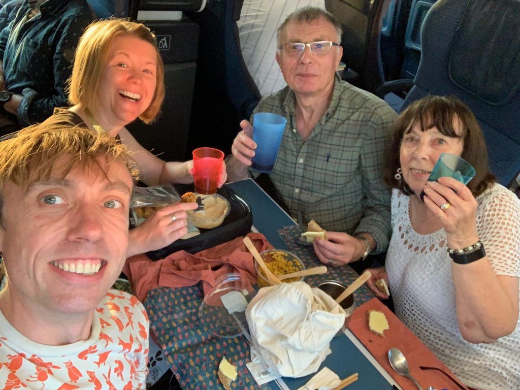 Four people sat at a train carriage table with glasses of wine and a food in front of them
