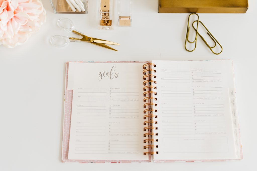 A paper spiral bound notebook open showing a blank “goals” page. Intentions can be set on paper or digital. 