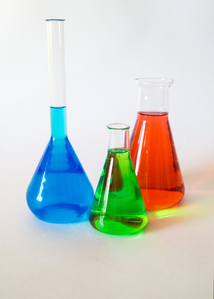 Three scientific looking beakers with coloured liquid inside.