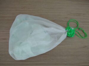 Home compostable bag cut up and inside a net bag