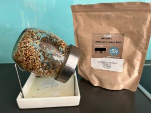 Sky Sprouts pouch next to sprouter with seeds for sprouting inside.