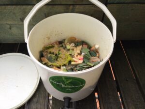 White plastic round Bokashi bucket with food waste inside