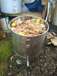 Metal round Bokashi bin open and full of food waste